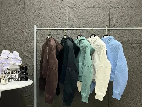Hoodies in brown, dark green, mint, cream and blue hanging on a clothes rail